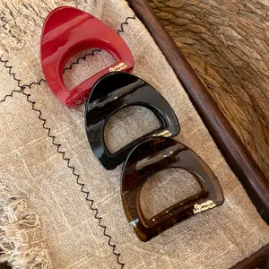 Gros plan de pinces à cheveux en acrylique rouge, noir et motif écaille de tortue
