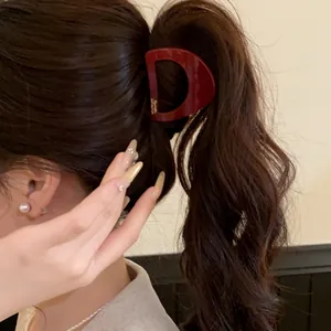 Vue rapprochée d'une pince à cheveux minimaliste en acrylique bordeaux en forme de D