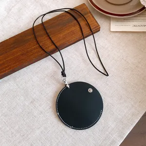 Detail view of a minimalist circular black leather pendant with adjustable cord necklace