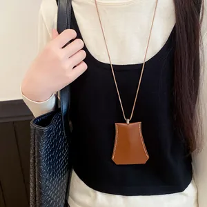 Detailed view of a brown leather eyewear holder necklace pendant with contrast stitching.