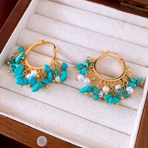 Detailopname van vintage 18k vergulde oorringen met turquoise stenen en parels