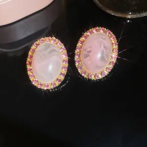 Macro-detail van luxe roze ovale oorbellen met een sprankelende zirkoon-halo