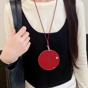 Close-up detail of a stylish red circular leather pendant necklace with matching cord
