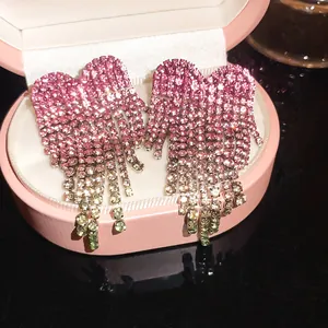 Gedetailleerde close-up van de sprankelende roze strass-oorbellen met franje detail