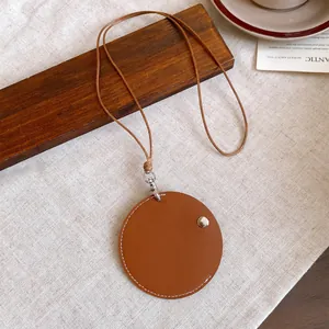 Detailed close-up of a brown leather circular pendant with white stitching on a matching cord.