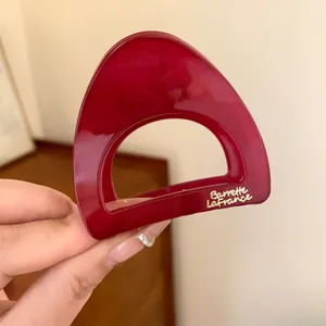 Vue détaillée d'une petite pince à cheveux en acrylique rouge avec lettrage doré