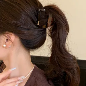 Gros plan d'une petite pince à cheveux en acrylique brun foncé pour une queue de cheval