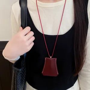 Detail view of a burgundy leather pendant necklace on a red cord.