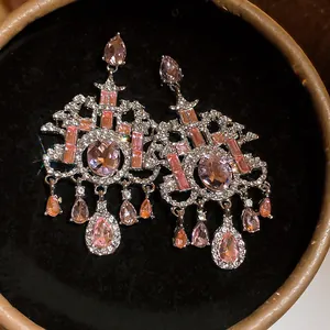 Detailopname van roze kristallen kroonluchter oorbellen met peervormige druppels in doos