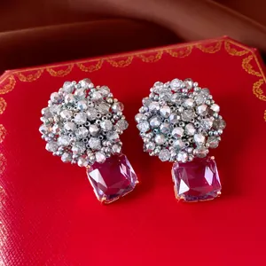 Macro detail of elegant beaded circular earrings with a square purple stone pendant