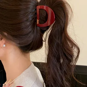 Gros plan détaillé d'une pince à cheveux en acrylique bordeaux en forme de D élégante
