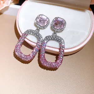 Macro-opname van elegante oorbellen met roze gradiëntkristallen en vierkante stenen