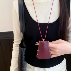 Close-up detail of a minimalist burgundy leather clochette necklace with white stitching