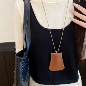 Close-up of minimalist brown leather trapezoid pendant necklace with white stitching