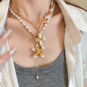 Detailaufnahme einer Halskette mit Perlen, Goldkette und metallischen Blumenanhängern