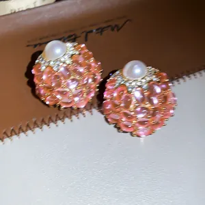Detailopname van elegante roze cluster oorknopjes met parel en glanzende zirkoniasteentjes.