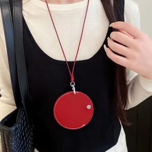 Detailed close-up of a stylish red circular leather pendant necklace worn on a black top
