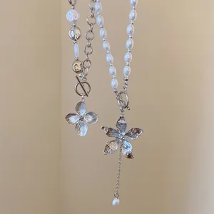 Detailansicht einer Perlenkette mit großem Metallblumenanhänger und OT-Verschluss.