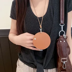 Stylish tan leather round pendant necklace and eyeglass holder worn by an elegant model