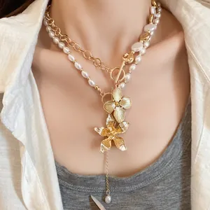 Nahaufnahme der mehrlagigen Perlenkette mit goldenen Blumenanhängern und OT-Verschluss