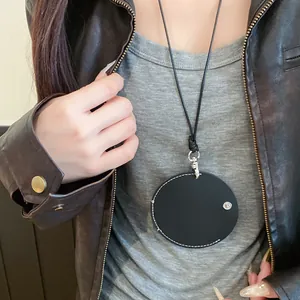 Close-up of a circular black leather eyeglass holder necklace worn over a stylish jacket