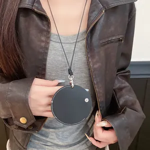 Close-up of a round black leather pendant necklace worn on a vintage leather jacket.