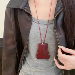 Detail of a burgundy leather clochette necklace with white stitching on a red cord.
