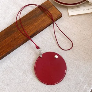 Detail of a minimalist red leather circular pendant necklace with stitching