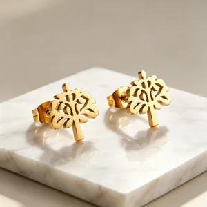Makroaufnahme von eleganten Lebensbaum-Ohrsteckern aus Gold auf einer weißen Marmorplatte
