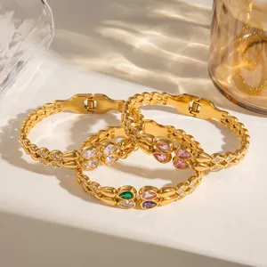 Detailed shot of three gold stainless steel bangles with teardrop-shaped zircons.