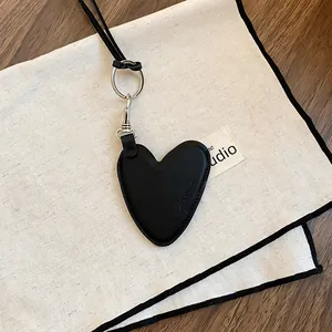 Gros plan d'un pendentif cœur en cuir noir vintage avec coutures fines et fermoir en métal argenté