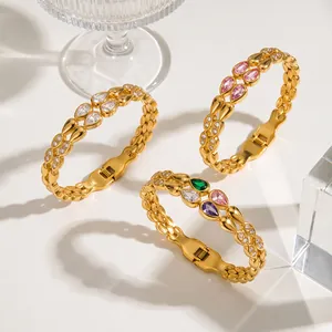 Detail of golden stainless steel bangles featuring colorful teardrop zirconia stones.