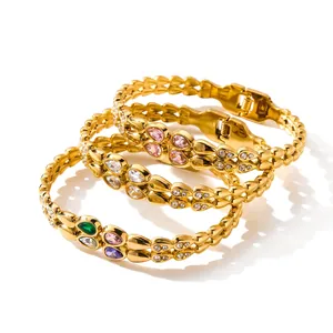 Close-up detail of three gold-plated stainless steel bangles with colorful teardrop zircons.