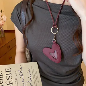 Vue détaillée d'un collier avec pendentif cœur en cuir bordeaux sur un mannequin.