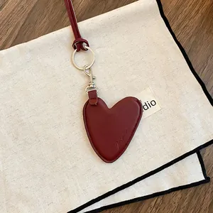 Gros plan d'un pendentif cœur vintage en cuir rouge foncé avec coutures fines