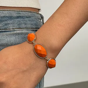 Detail shot of a retro geometric bracelet with orange resin stones on a model's wrist