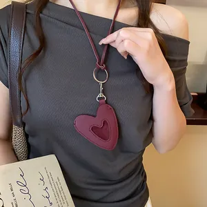 Vue détaillée d'un pendentif cœur en cuir bordeaux vintage sur un haut gris côtelé