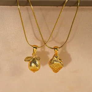 Close-up of 18K gold plated strawberry and lemon pendants on stainless steel necklaces.