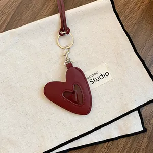 Gros plan d'un pendentif cœur en cuir bordeaux vintage avec fermoir sur toile écrue