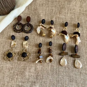 Vielfältige Vintage-Boho-Ohrringe mit Holz und Muscheln auf Sackleinen-Hintergrund