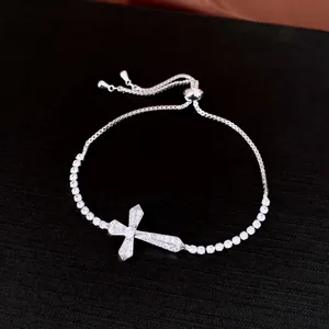 Detailed view of a silver-toned adjustable bracelet with zircon-encrusted cross pendant