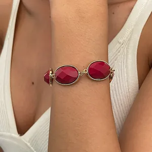 Close-up of a vintage gold metal bracelet with burgundy oval resin geometric stones