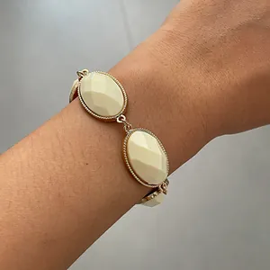 Detailed view of a retro geometric bracelet with cream oval resin stones on a wrist