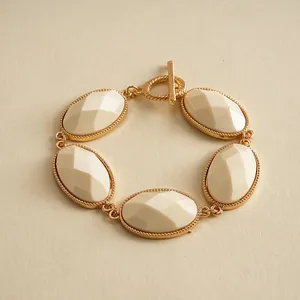 Macro view of vintage gold-toned bracelet featuring five faceted cream resin oval stones.