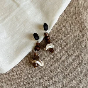 Detailansicht der ethnischen Ohrringe aus Holz und Muscheln auf Leinenhintergrund.