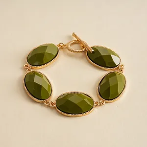 Close-up of retro gold-toned bracelet with faceted olive green oval resin stones