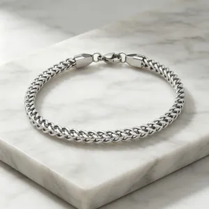 Detailed view of a 3mm stainless steel franco chain bracelet resting on white marble