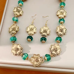 Nahaufnahme eines Vintage-Blumenschmucksets in Gold mit grünen Harzperlen auf einem Tablett