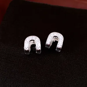 Close-up of sparkling cubic zirconia horseshoe earrings on black textured fabric