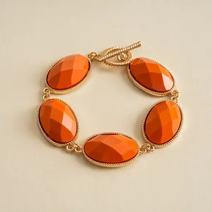 Detail of vintage gold-tone bracelet with faceted orange oval resin stones and toggle clasp.